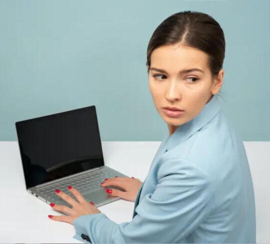 person looking over shoulder from laptop